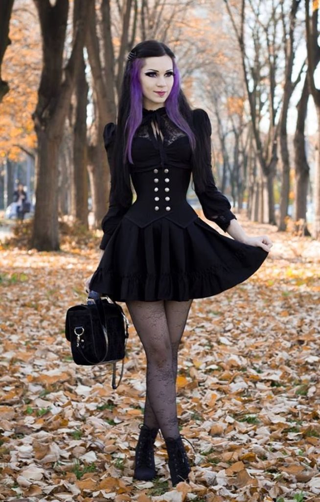 girl with black and purple hair in black dress in a park 